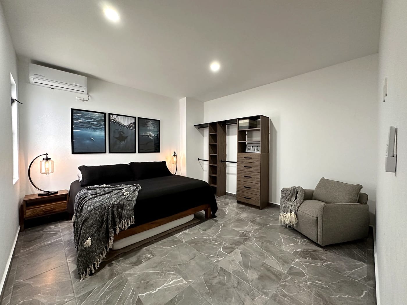 Bedroom with open closet, dresser and armchair