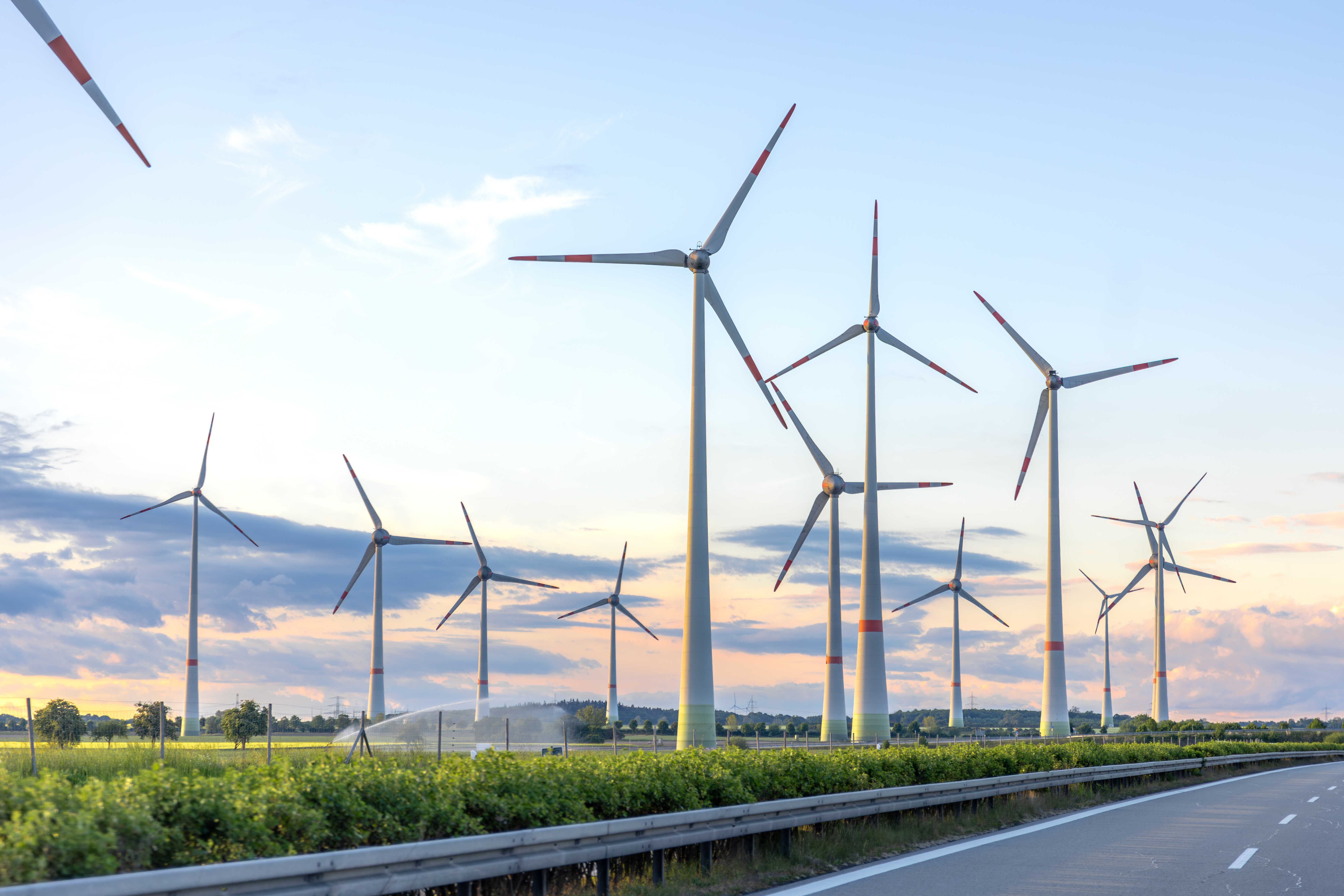A large wind turbine in a field with a clear blue sky, representing renewable energy.