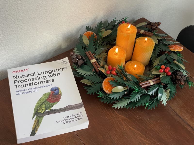Natural Language Processing with Transformers book by O'Reilly, placed on an Advent wreath with orange candles