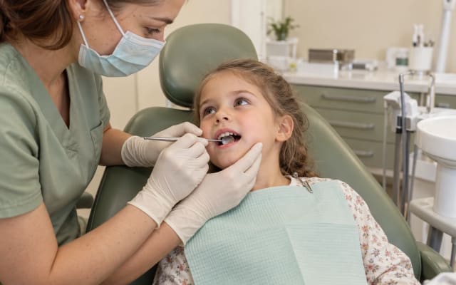Dentist examining a child’s baby teeth.
