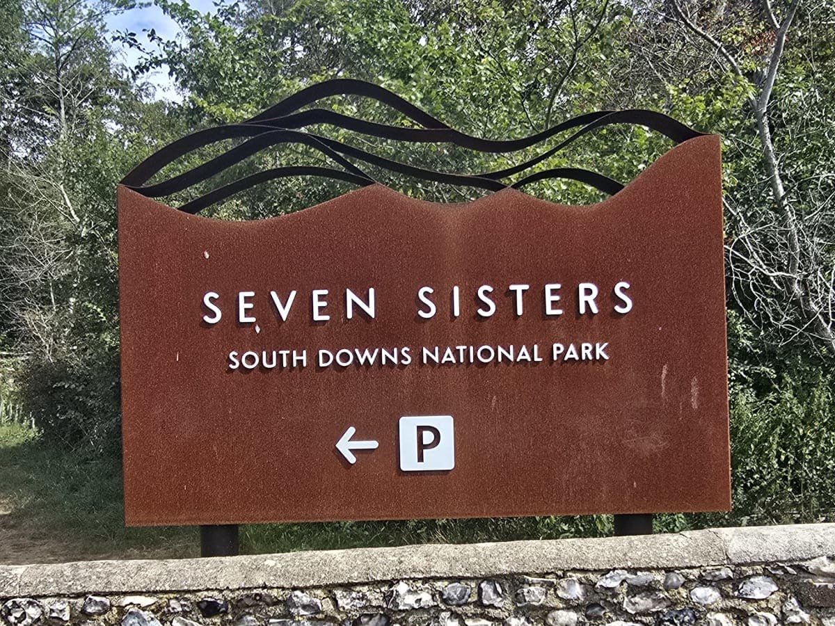 Wooden trail sign for the Seven Sisters, South Downs National Park, with a car park arrow
