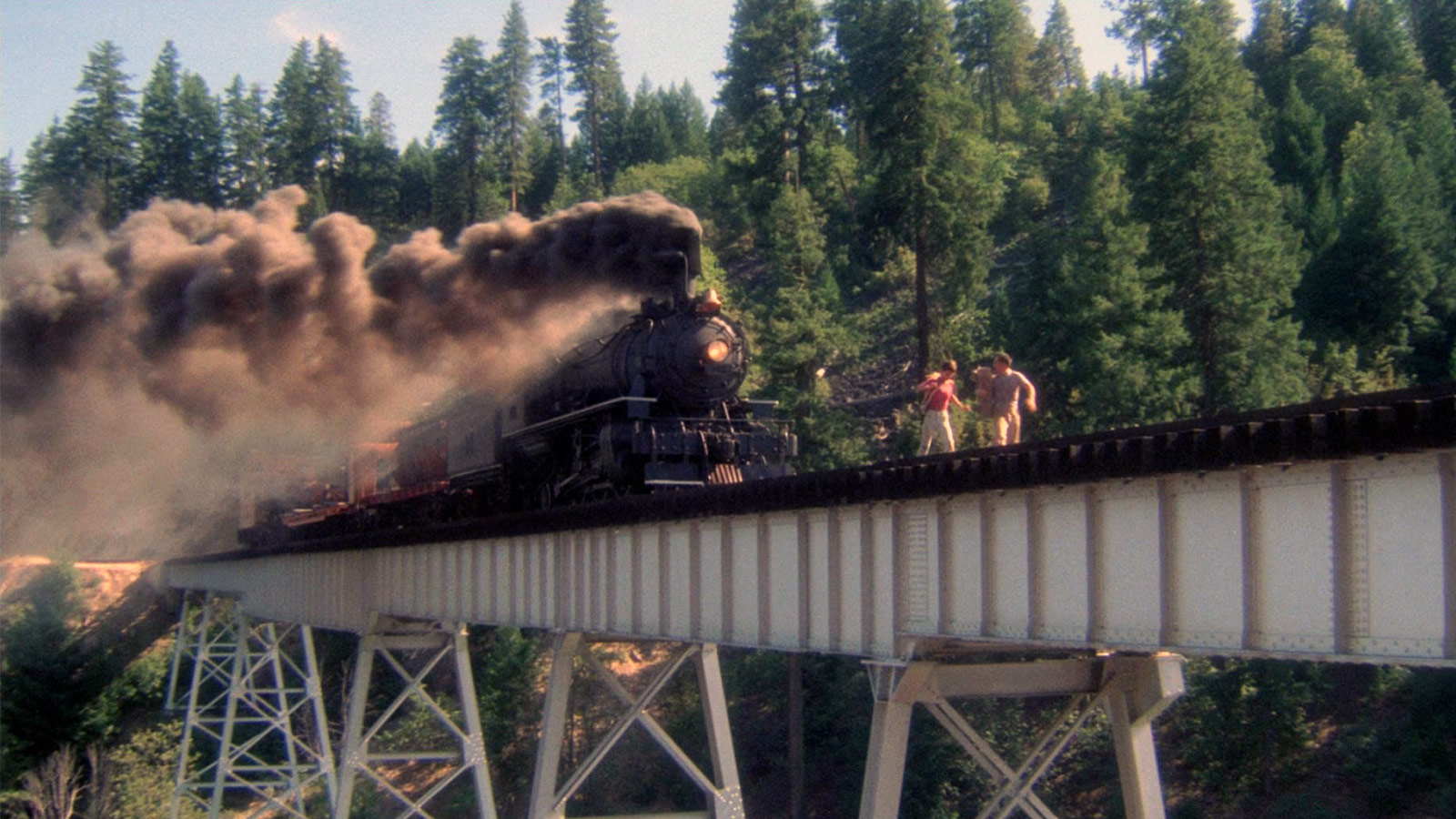 two boys running away from a train on a bridge