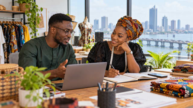 Two Nigerian small-business owners reviewing a customer pipeline and planning business development together