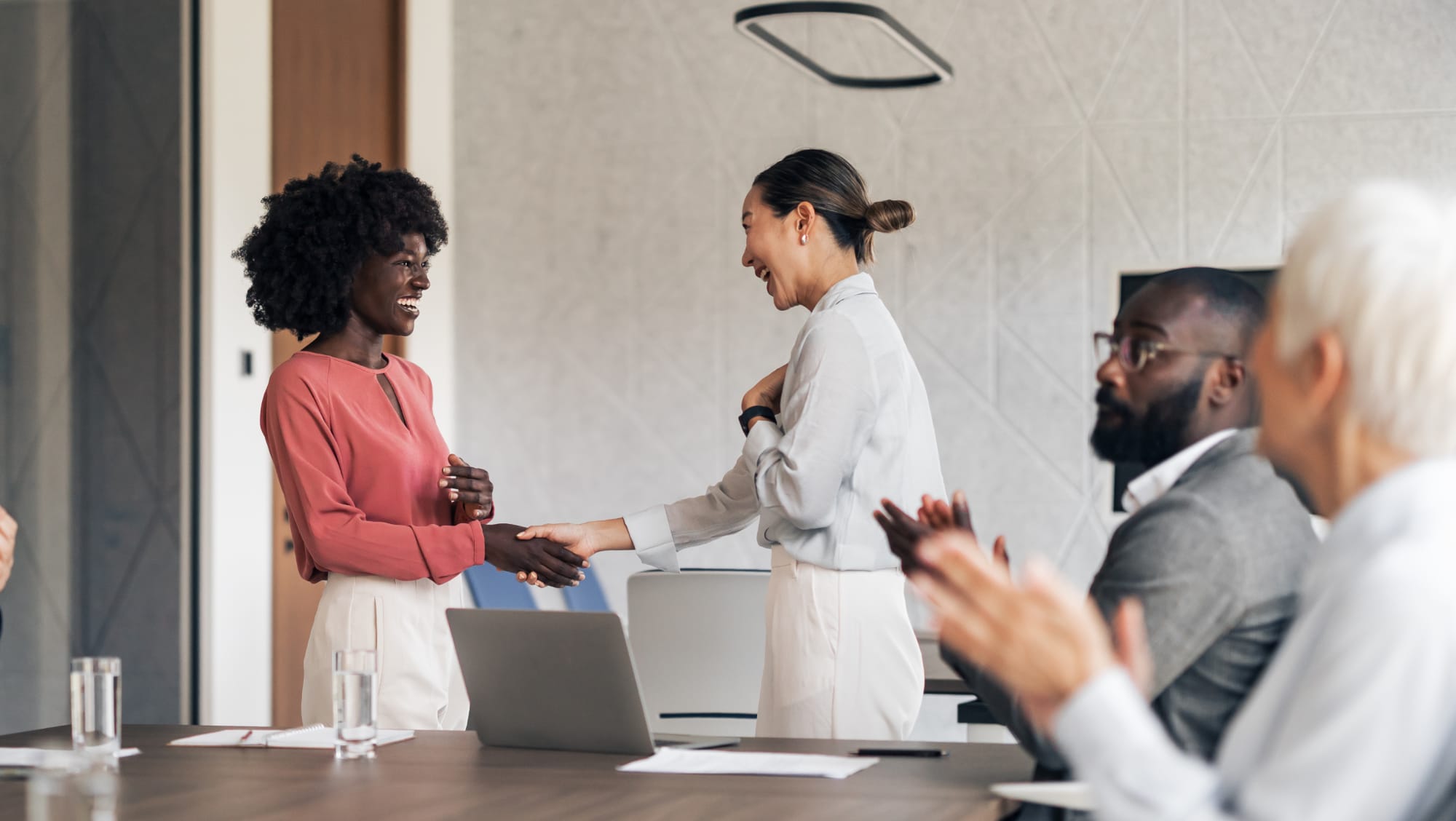 two-people-shake-hands-in-a-conference-room