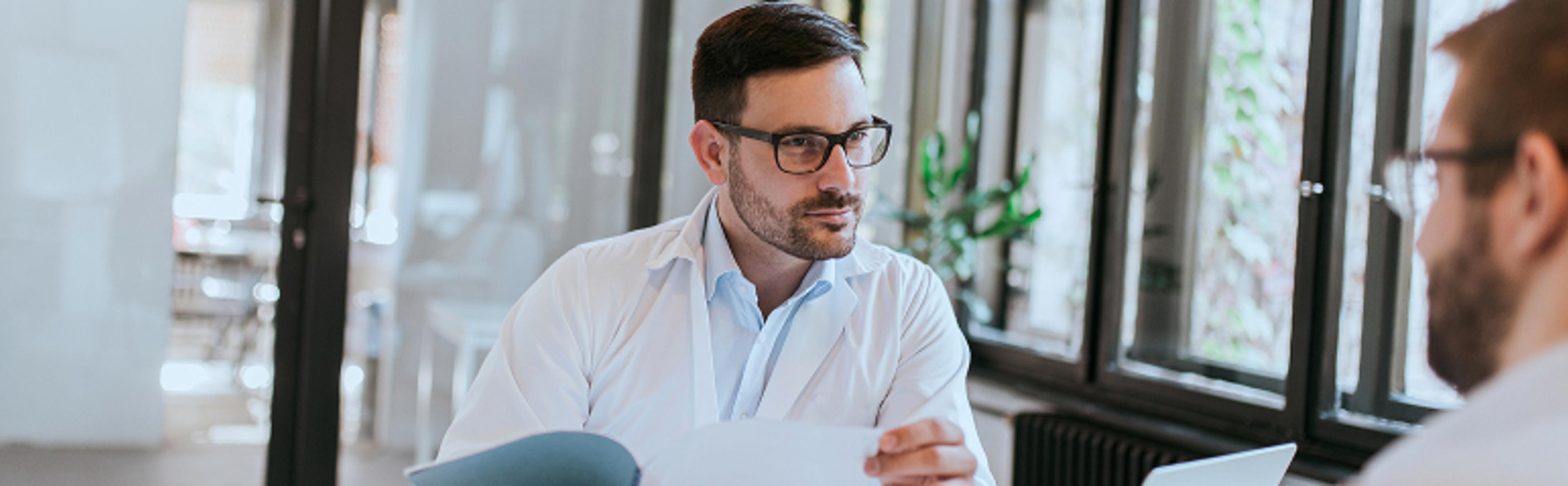 Two individuals in a meeting room, one holding papers