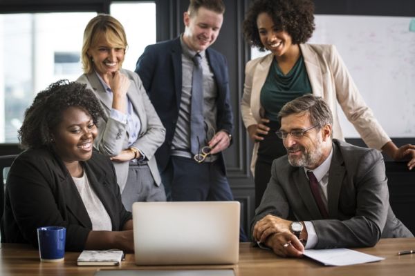 group of employees smiling around a computer