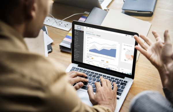 man typing on computer while colleague explains