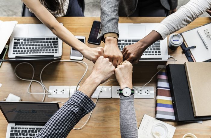 diverse employees fist bumping over their workspace