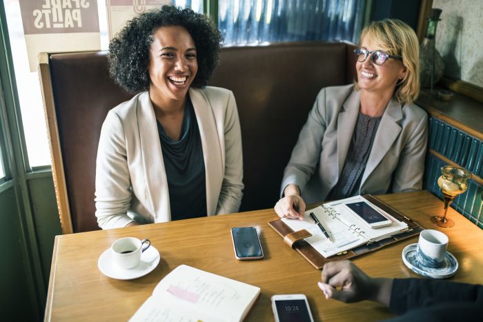 two women sitting at a table laughing, having a good time