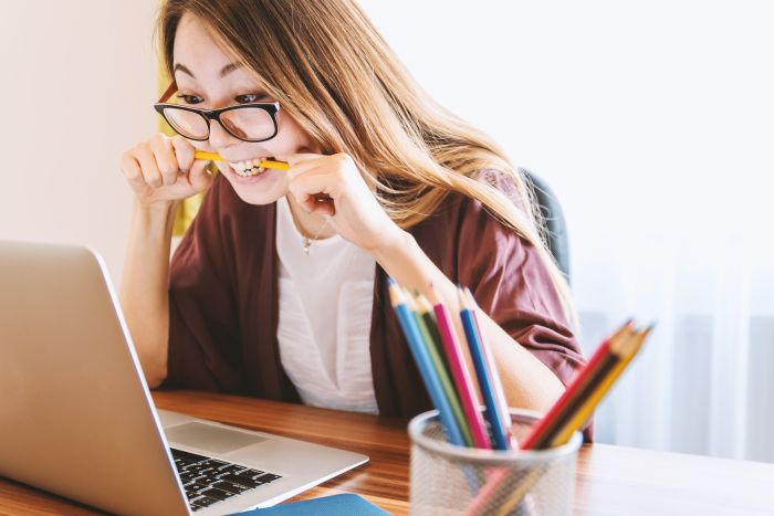 woman frustrated with technology, chewing on her pencil