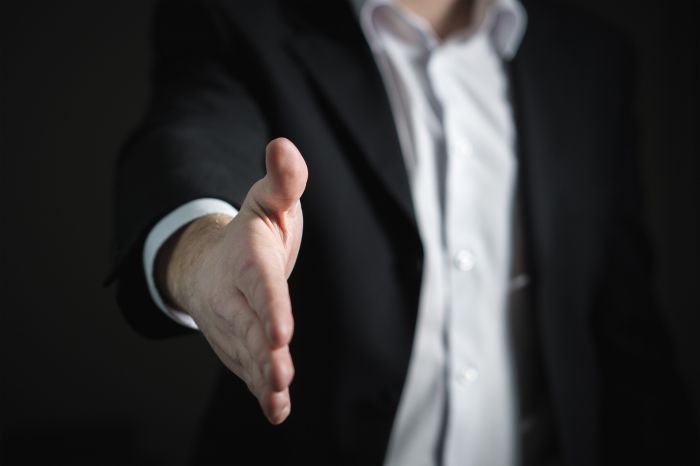 man in business suit extending his hand to shake