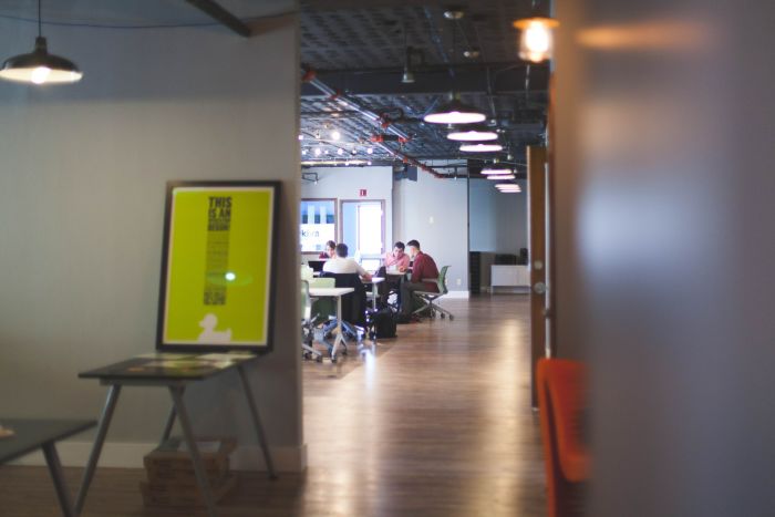 different view of an open office plan, with employees in the background sitting at a table having a discussion