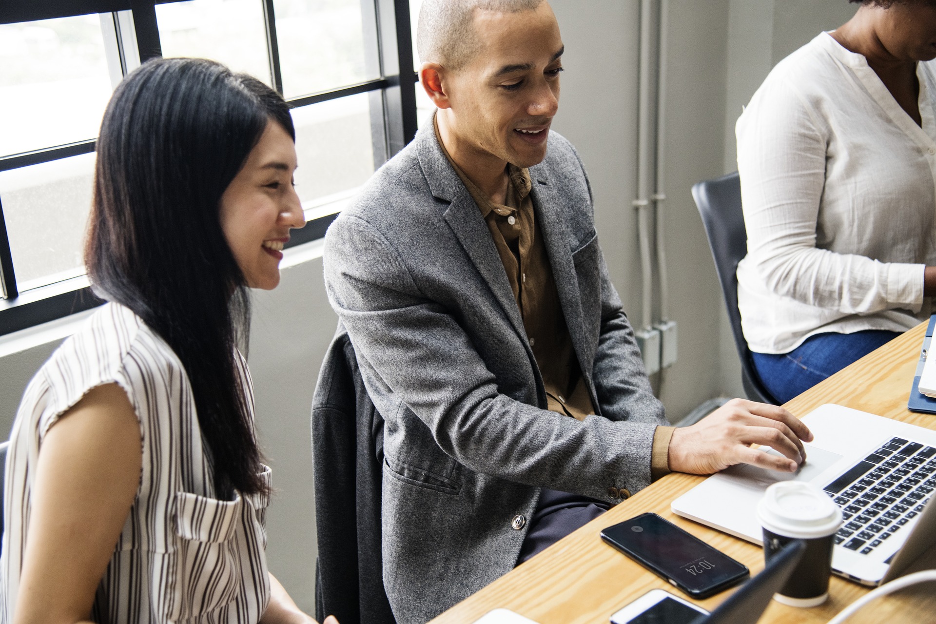 two business professionals in a positive work environment smiling looking at computer screen