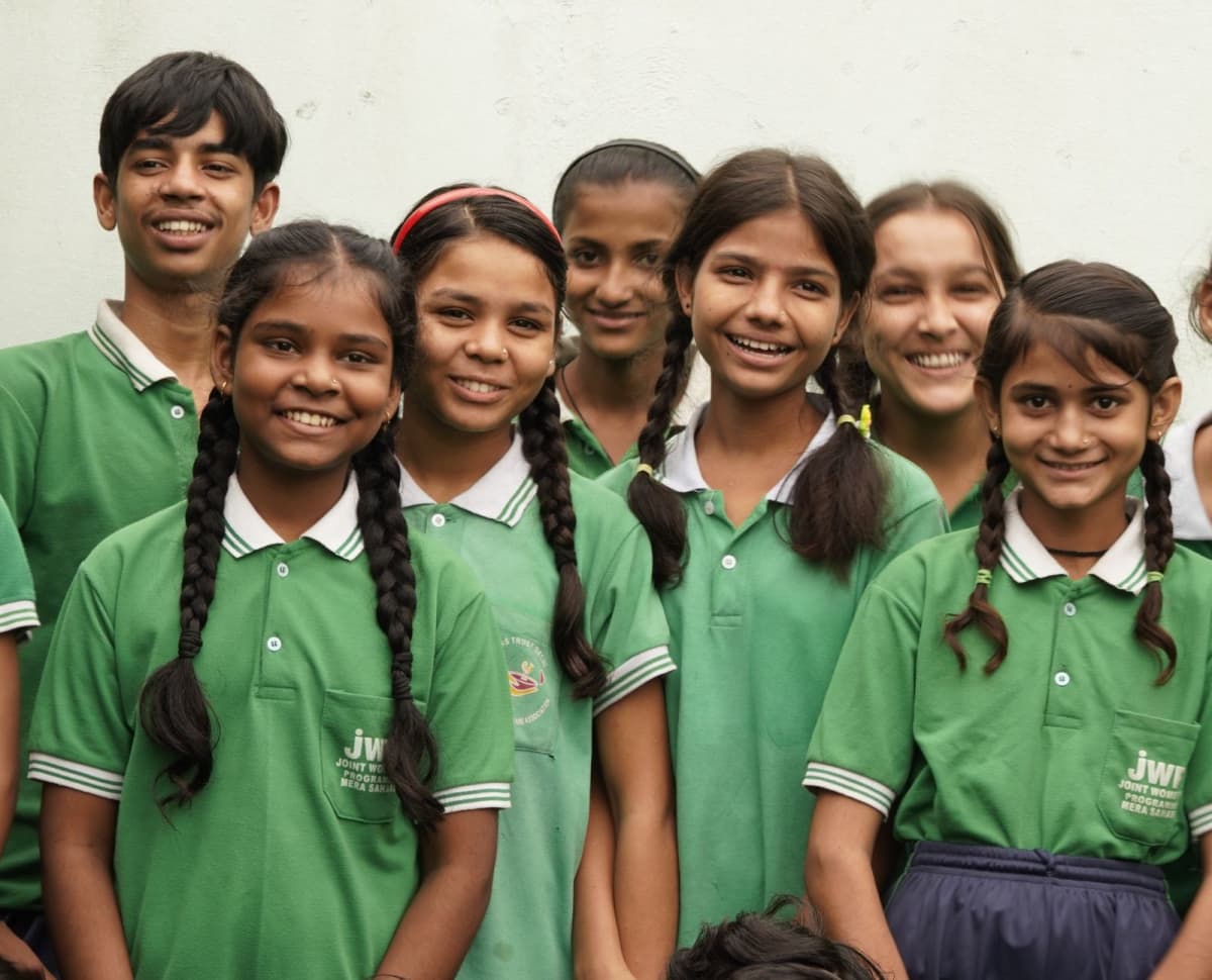 Children in green Joint Women’s Programme uniforms smiling together