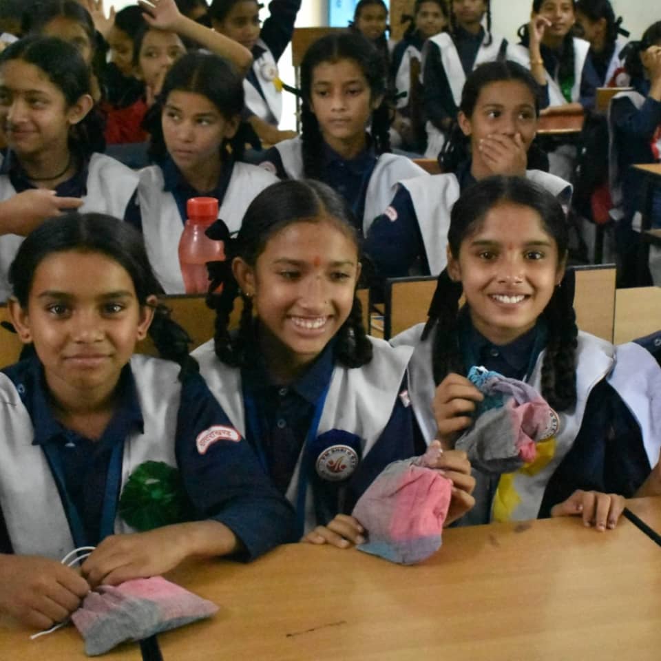 Schoolgirls smiling in class holding handmade pouches