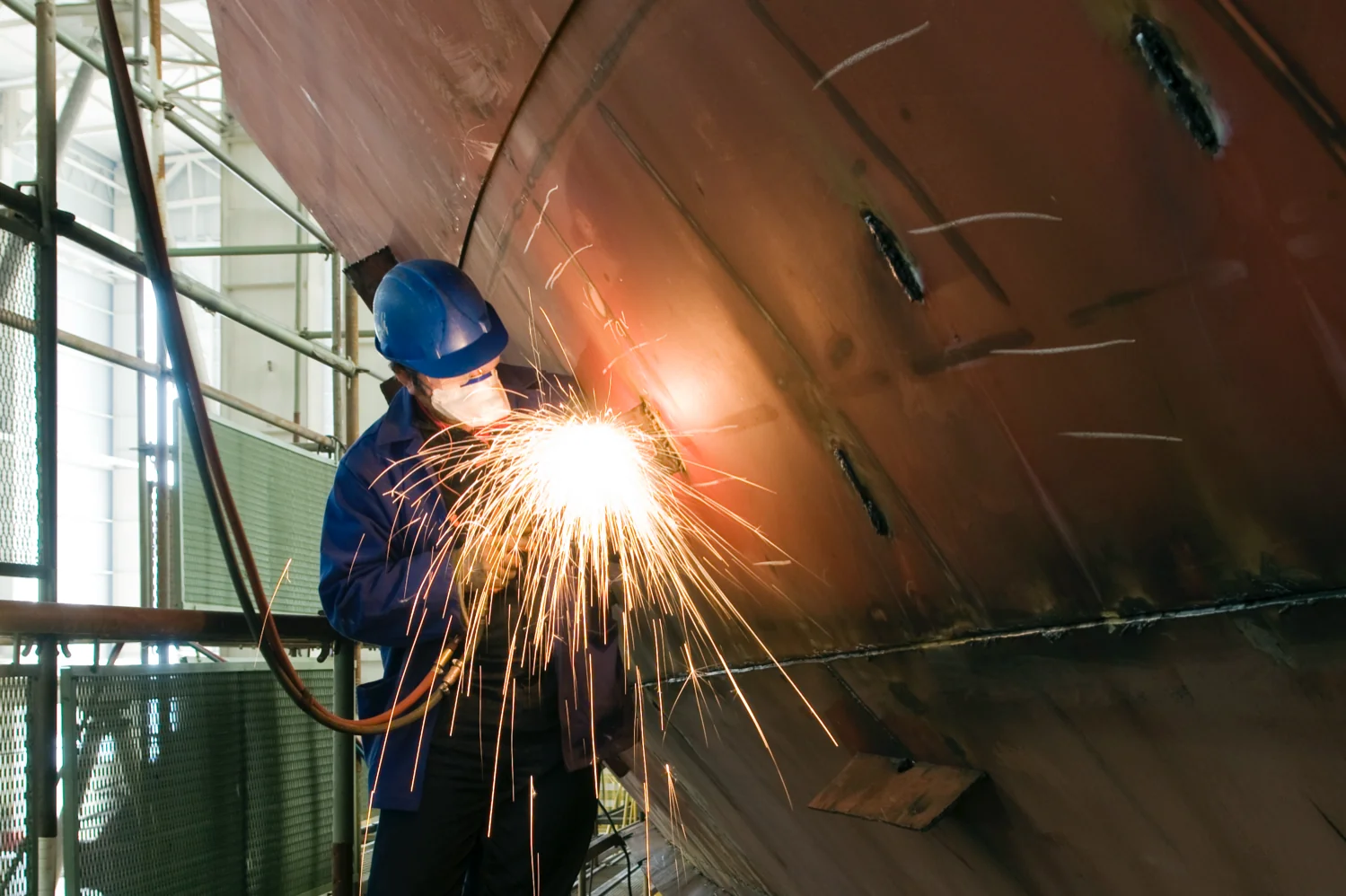 A man making a weld on the hull of a boat.