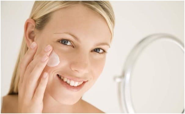 женщина наносит крем на кожу лица