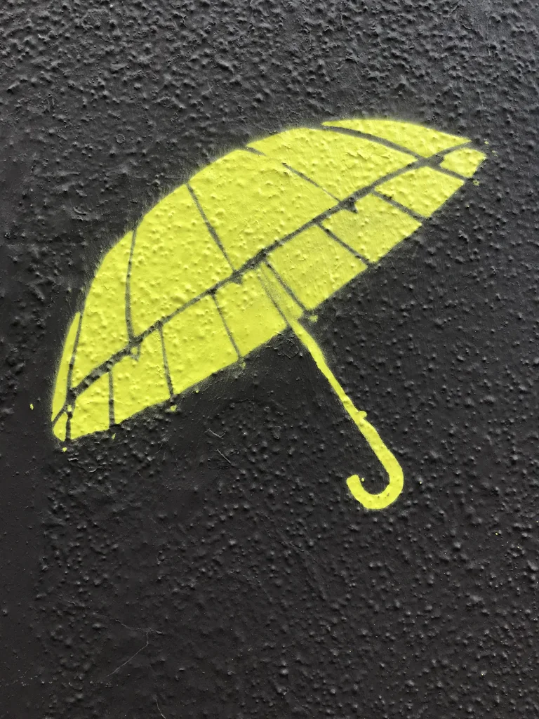 En stencil af en paraply på asfalt