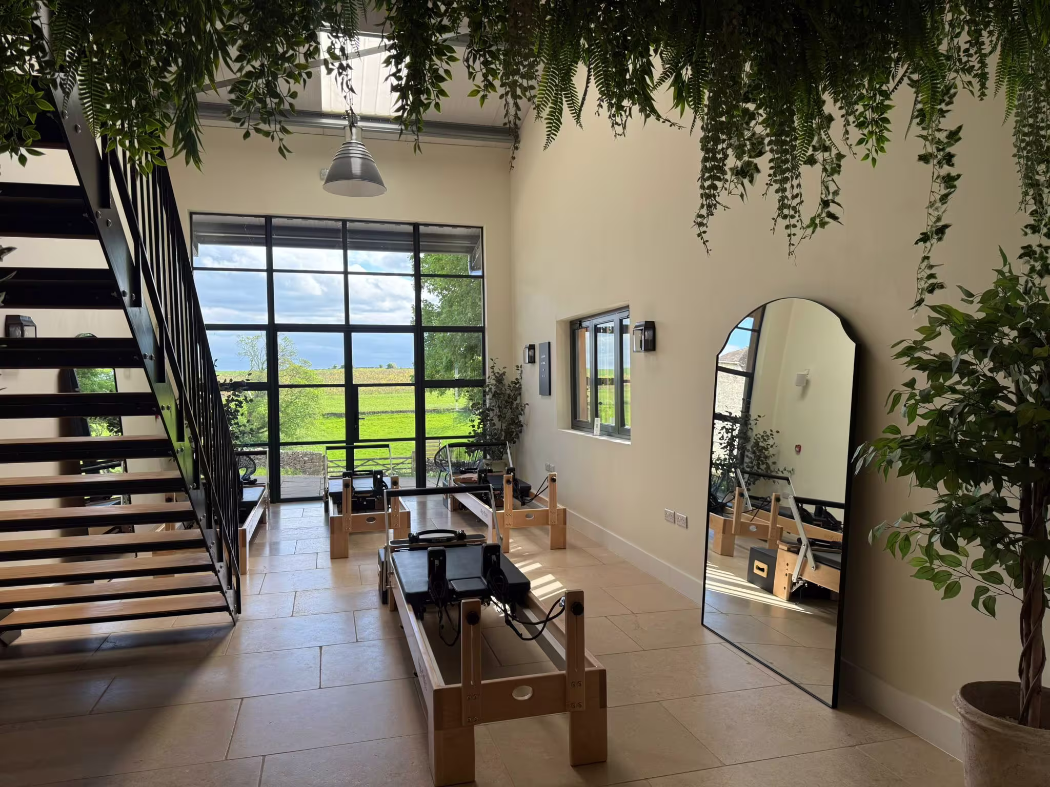 Inside the Reformer Room studio, with a view of the Cotswolds countryside through large windows.