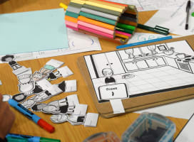 Arts and crafts materials on a table, coloured pens, illustration cutouts