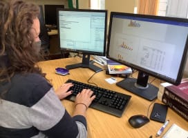 Person typing at computer with two screens