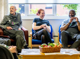 Three people sat down talking and smiling