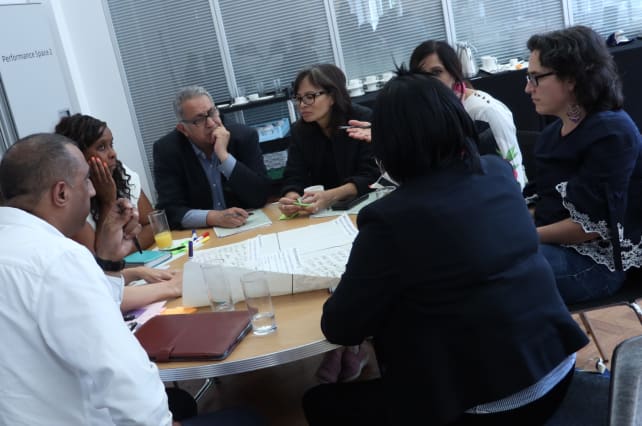 Group of people sat around a desk talking