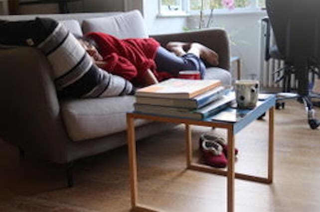 A person sleeping on the sofa under blankets