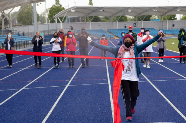 Shanali crossing the finish line of the walking challenge with a smile on her face and arms in the air