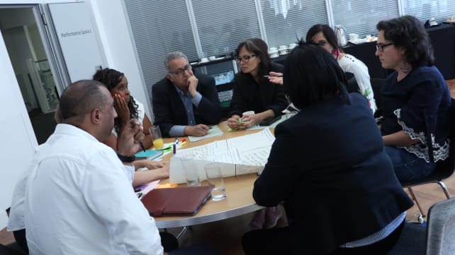 Group of people sat around a desk talking