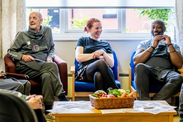 Three people sat down laughing and smiling