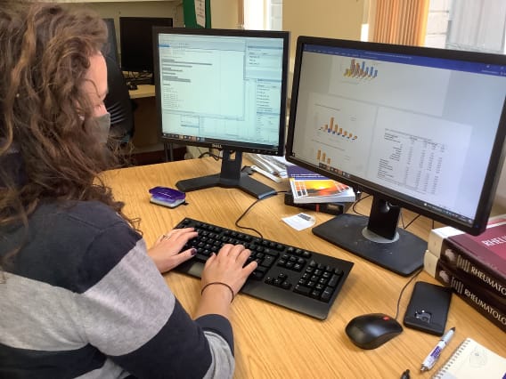 Person typing at computer with two screens