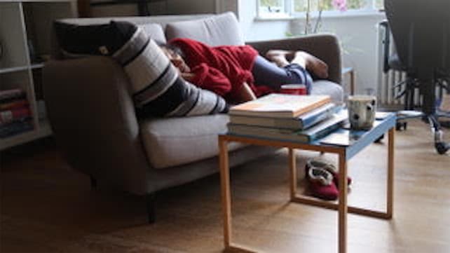 A person sleeping on the sofa under blankets