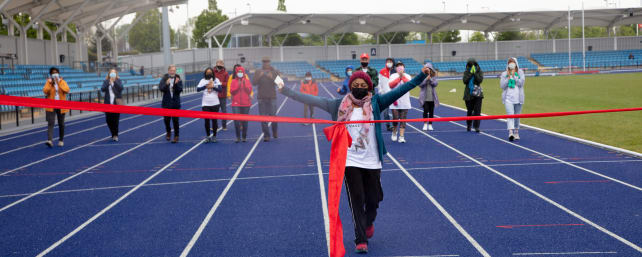 Shanali crossing the finish line of the walking challenge with a smile on her face and arms in the air