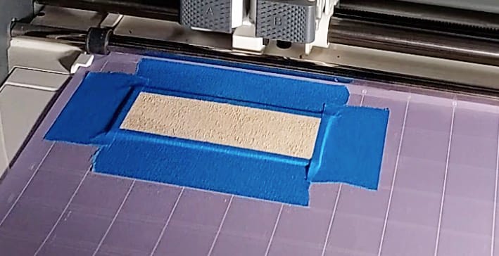 Leather prepared for cutting Shows the leather sample stuck to the StrongGrip Cricut mat using StrongGrip transfer tape. It has been secured on all 4 sides with painter's tape.