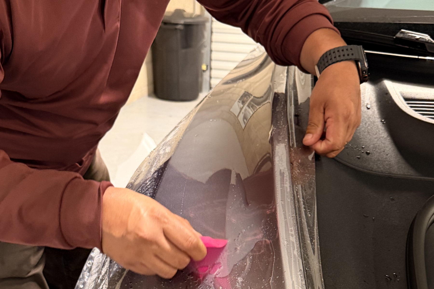 Technician applying stealth paint protection film with installation gel on a Tesla Model Y Juniper at CDA Auto Styling in Riverside, California.