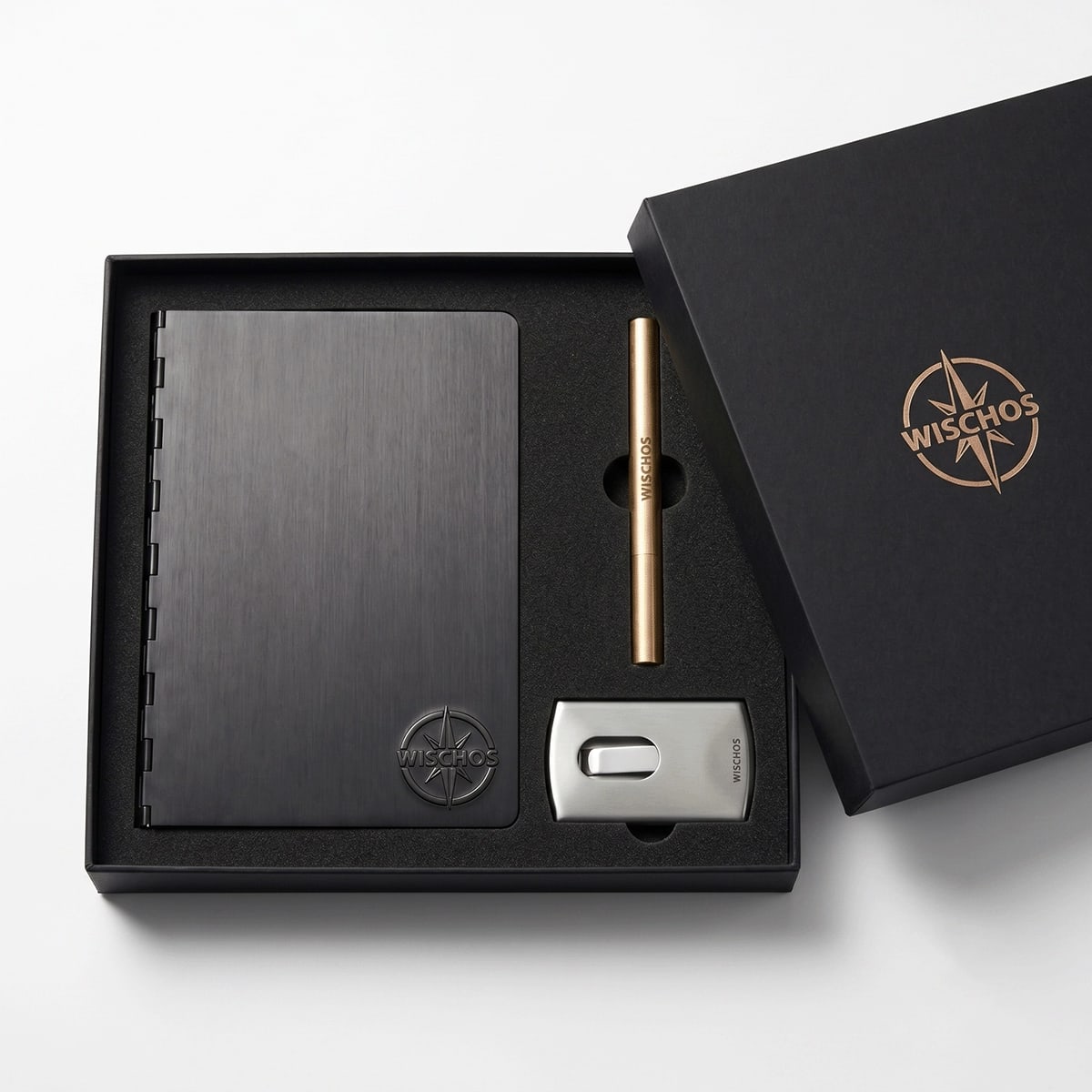 Three-piece custom metal business meeting gift set — anodised aluminium ring binder notebook, brass rollerball pen, and stainless steel business card case in rigid lid gift box with black EVA foam insert