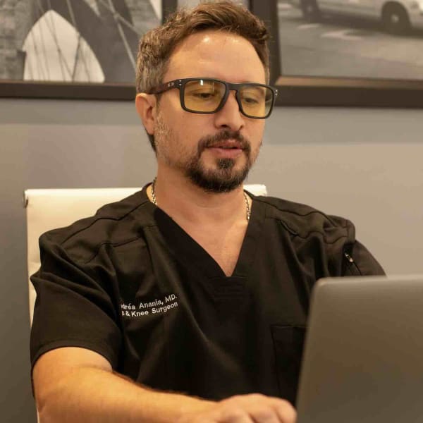 El Dr. Andrés Anania revisa un caso en su laptop, en el consultorio