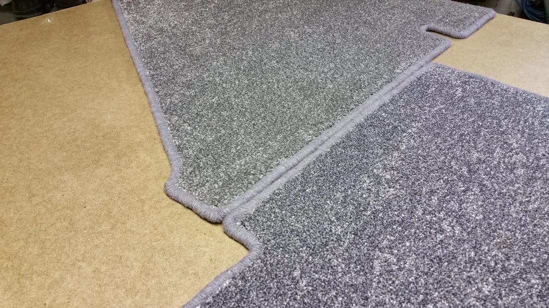 Close-up of a custom-shaped, grey carpet with whipped edging, made to fit a caravan floor