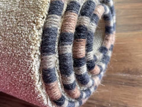 Close-up of colourful yarn whipping around a carpet edge