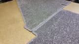 Close-up of a custom-shaped, grey carpet with whipped edging, made to fit a caravan floor.