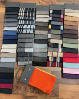 Multiple hangers of tape edge swatches in a variety of colours and patterns, displayed on a wooden floor.