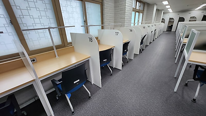 벽면을 따라 배치된 칸막이형 독서실 책상과 개별 조명, 콘센트가 갖춰진 모습