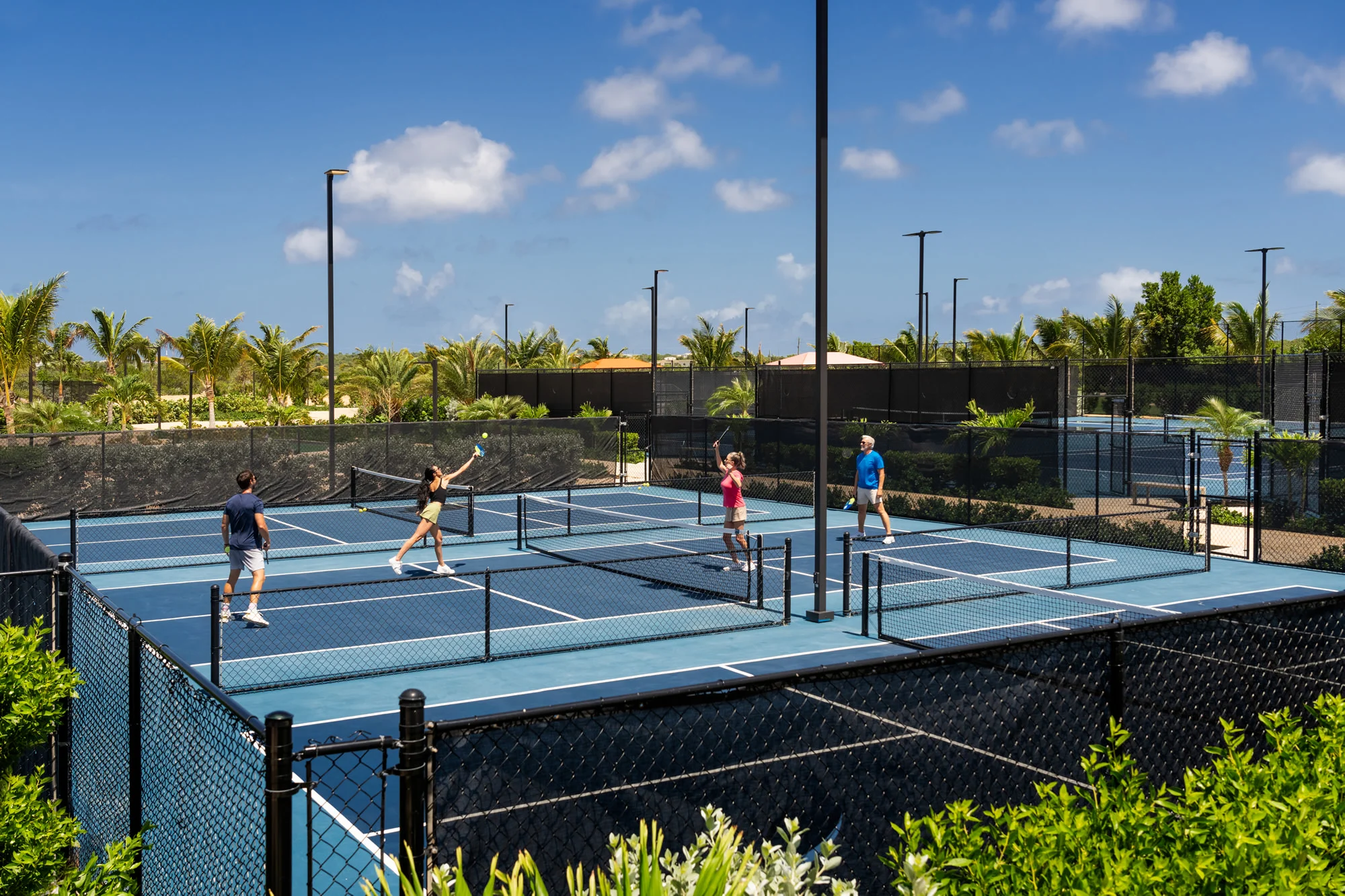Four adults playing doubles pickleball at a lush coastal resort