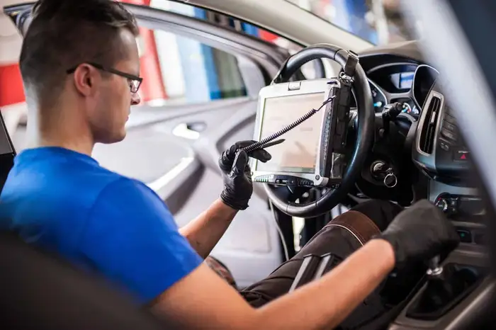 A technician performing a safety systems recalibration on a vehicle using advanced diagnostic equipment.