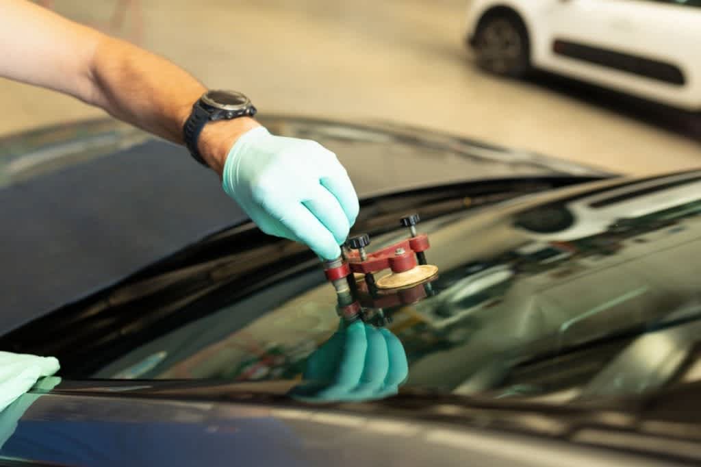Mechanic using repairing equipment to fix damaged windshield