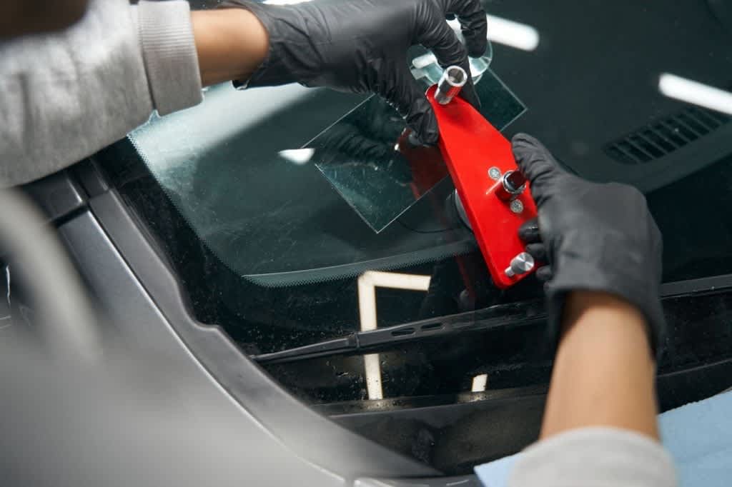 skilled worker mounting crack repair device on windshield
