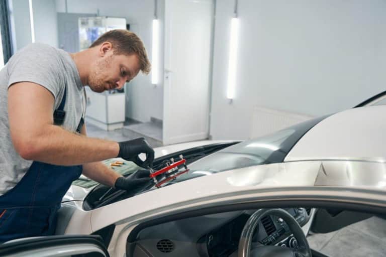 Closeup of man working with vacuum filler repair cracks in windshield