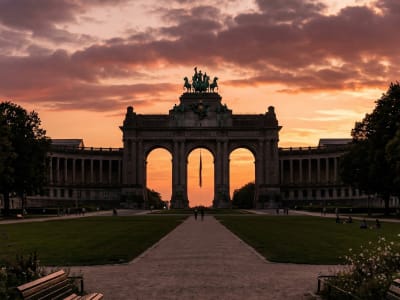The Triumphal Arch of the Cinquantenaire Park silhouetted against a dramatic sunset sky in Brussels, Belgium
