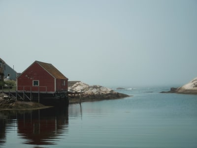 Red fishing shack reflected in calm harbour water, Peggy's Cove, Nova Scotia
